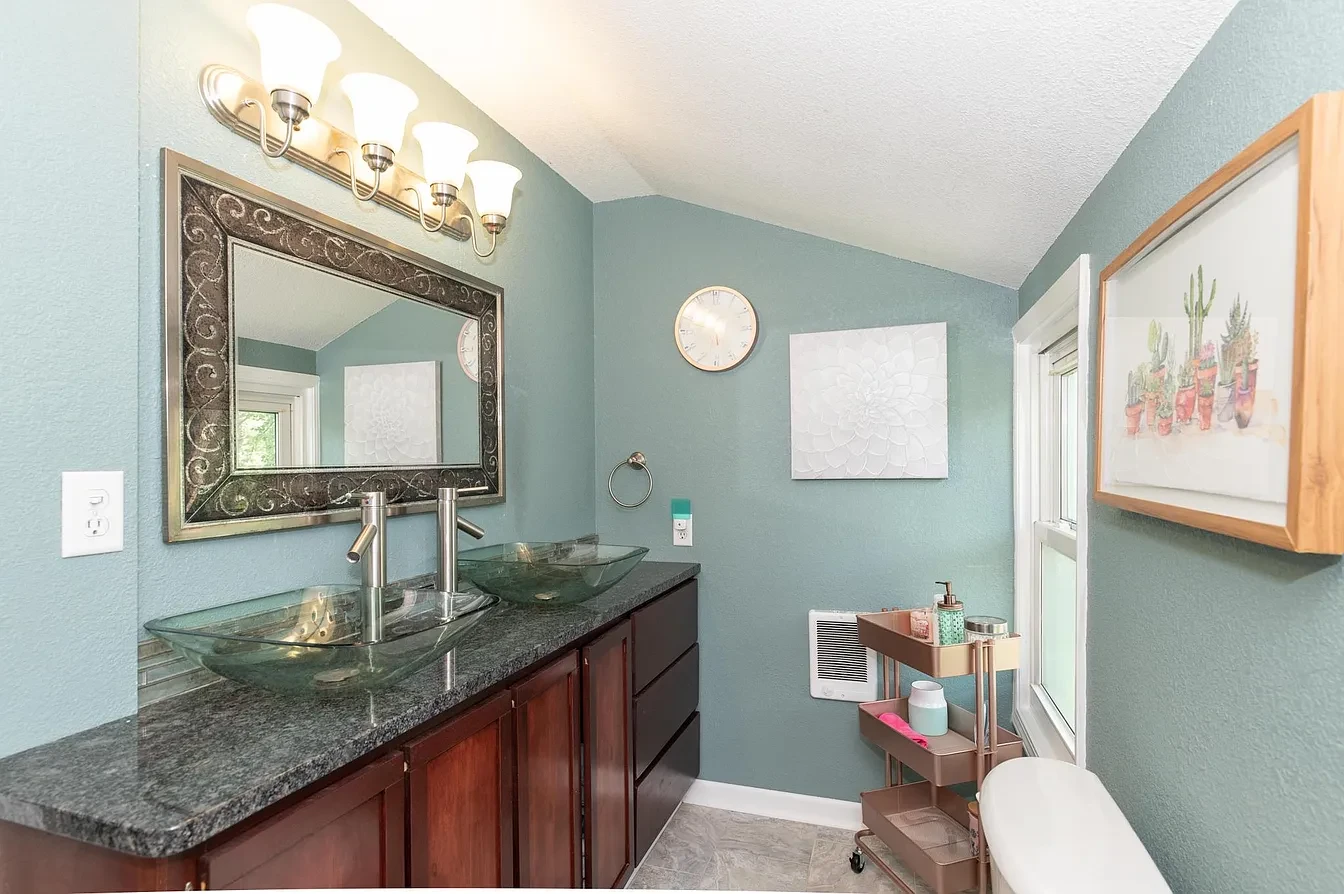 Bathroom — wide view of teal bathroom with dual vessel sinks and vaulted ceiling