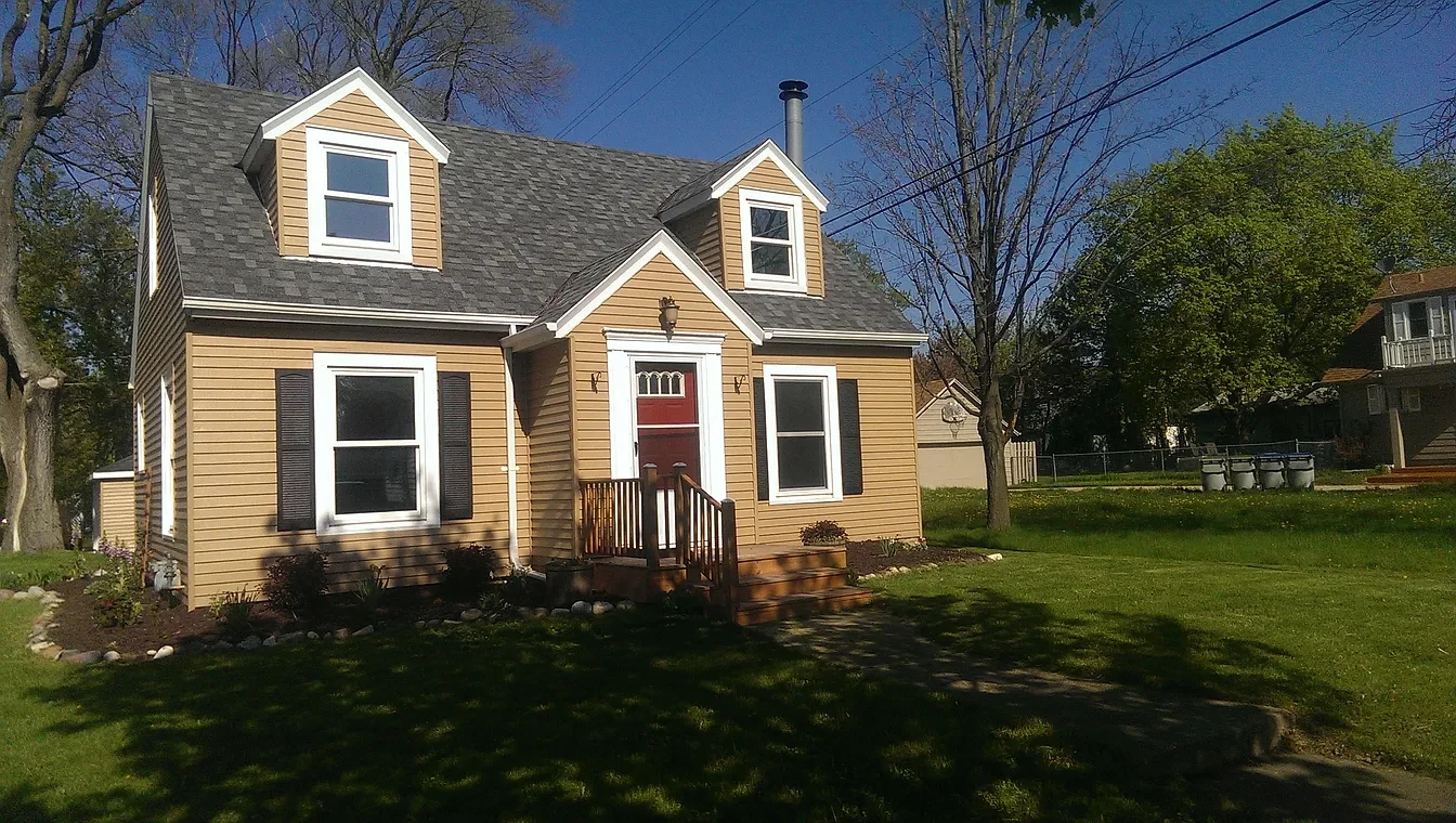 Exterior — tan cape cod with red door and cedar deck, spring