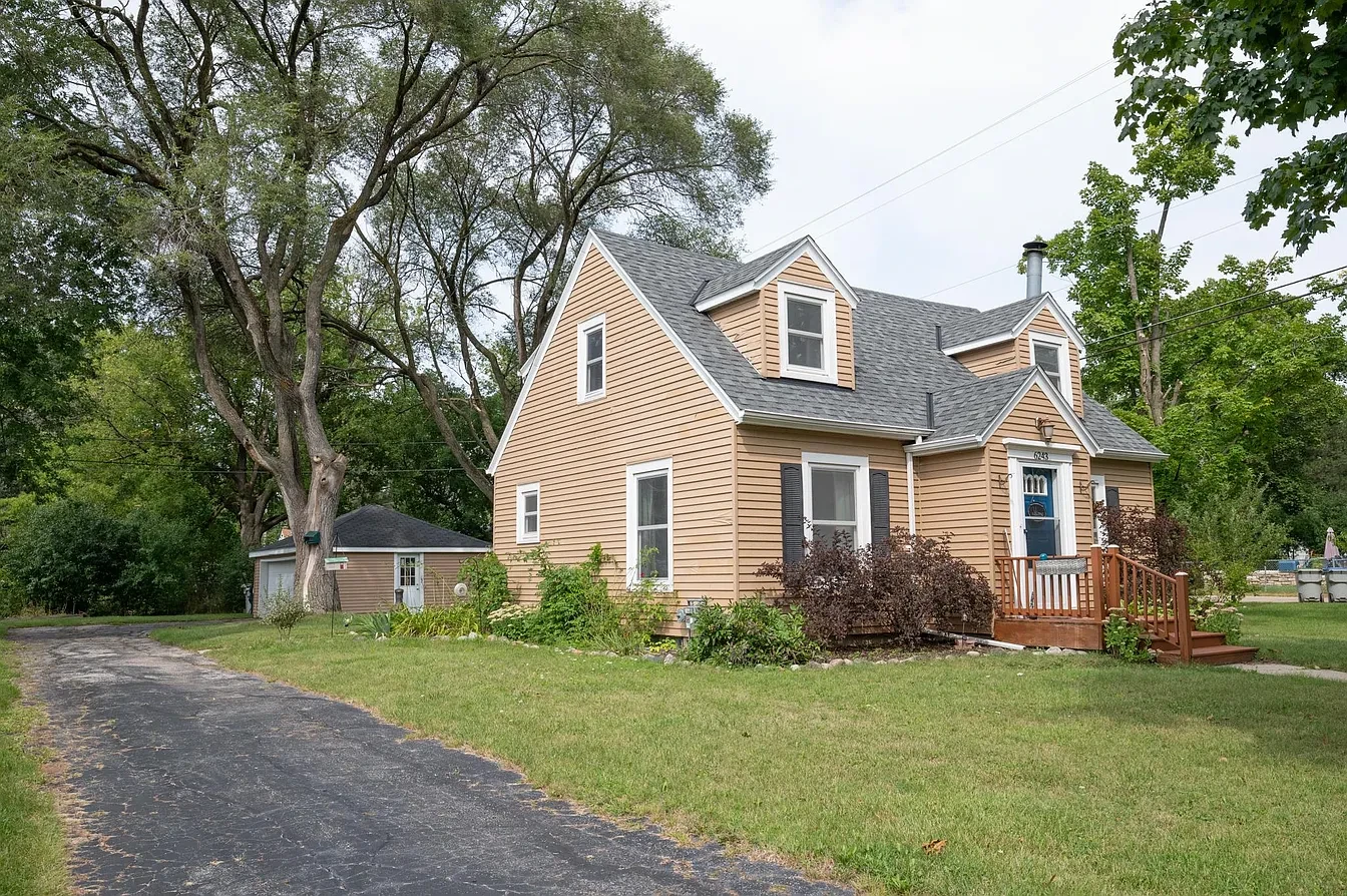 Exterior — tan cape cod with blue door and detached garage, summer