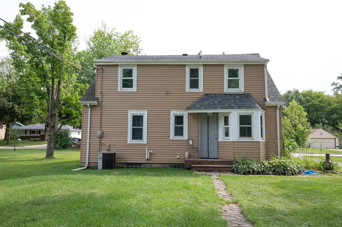 Exterior — tan two-story home rear entry with stone path