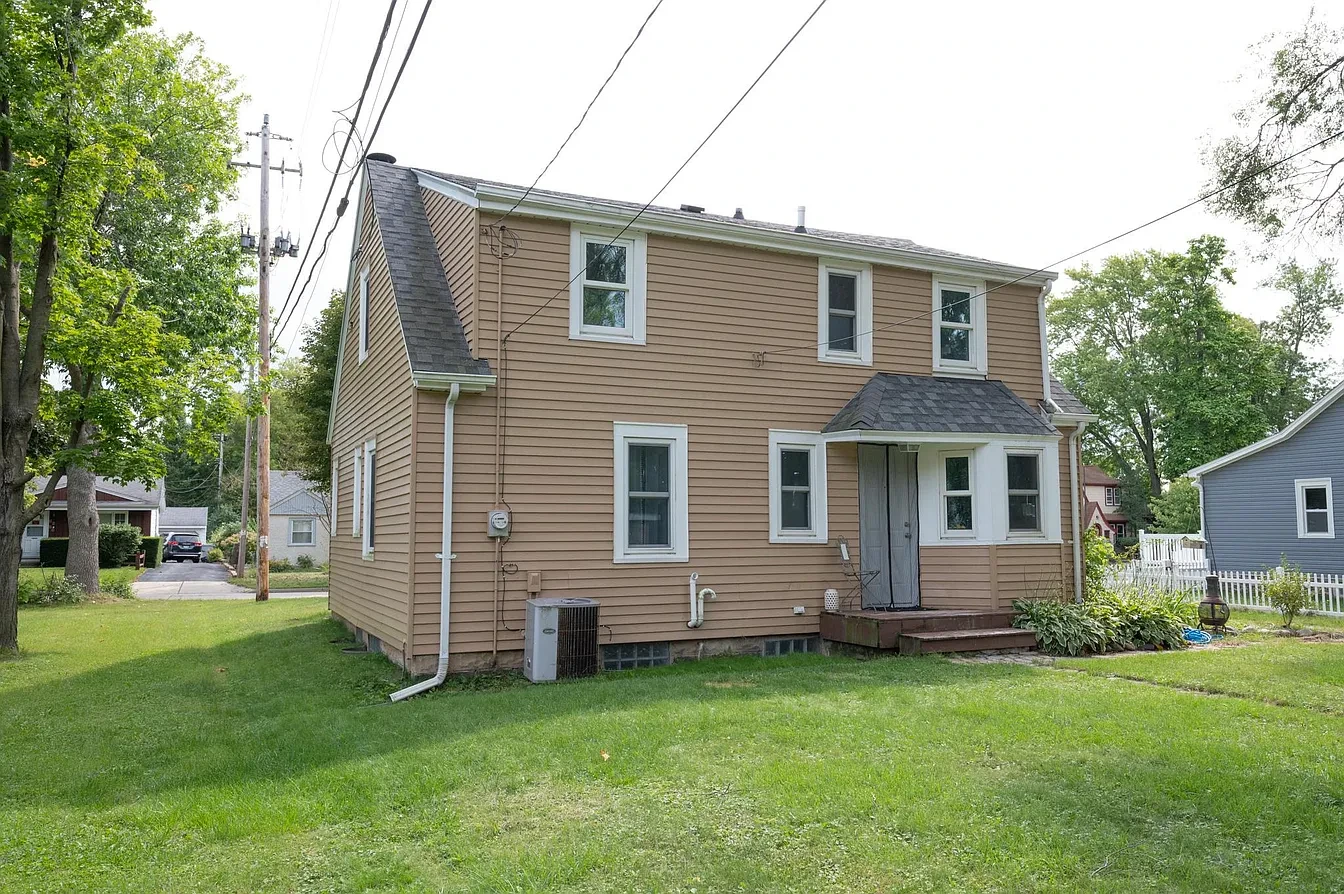 Exterior — tan two-story home side view with AC unit and lawn