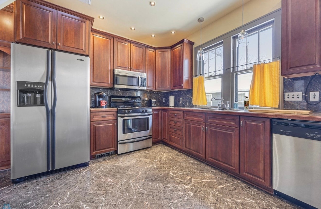 Kitchen — cherry cabinets with stainless appliances, marble floor and yellow curtains